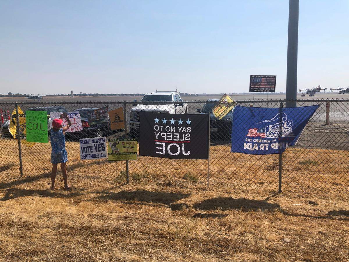 A child hangs an anti-Biden sign during a protest outside Mather Airport on Monday, Sept. 13, 2021. President Joe Biden arrived in California for wildfire briefings and an appearance at a campaign rally for Gov. Gavin Newsom, one day before the recall election.