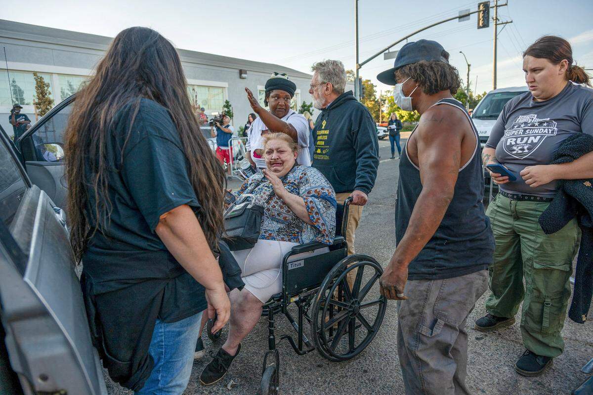 Camp Resolution attorney Anthony Prince pushes Shonn Adams in a wheelchair as he listens to Satearah Murphy, center, as she talks about trying to save Adams’ trailer inside Camp Resolution on Monday. Prince was moving Adams, who uses oxygen to breathe, from the encampment before the city cleared the camp. She was crying because she didn’t want to leave her dog or her home for the past two years.