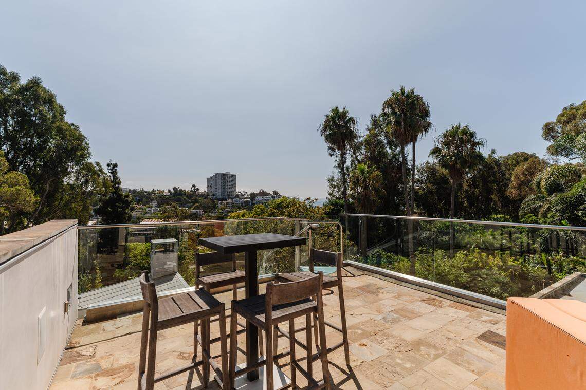 Mature landscaping and towering trees envelop this private, LEED Gold-certified home, offering tranquility and luxurious living just steps from the Pacific Ocean in the desirable Huntington, Palisades tract.