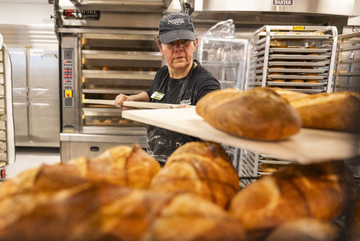 Vanessa Victor, a corporate support lead for Nugget Market, moves fresh baked loaves of bread at the grocery store chain's newest store — located in Rocklin — on Monday.
