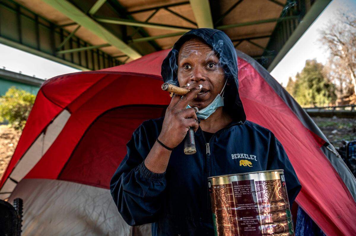 Timell Brown, 34, blows smoke from a cigar she found in a tin with some cigarette butts near her tent under a Sacramento freeway interchange on Jan. 19. She said she suffers from depression, anxiety and schizophrenia.