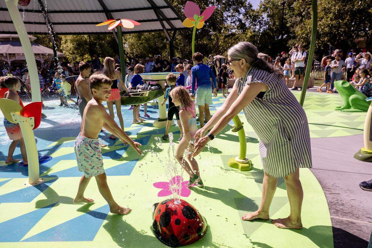 Lupe Corona, mother of slain Davis Police officer Natalie Corona, plays with her nephew Jackson Martinez at the opening of Natalie’s Corner Splash Pad in the city's Central Park on Saturday.