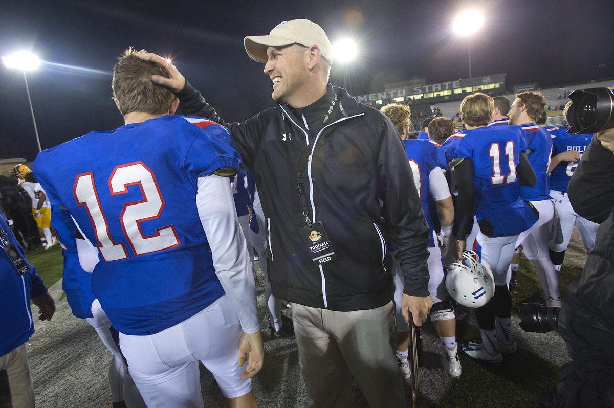Bulldogs Jake Browning (12) is congratulated by head coach Troy Taylor following the CIF Northern California Regional Division I football championship between the Folsom High School Bulldogs and the Grant High School Pacers at Hornet Stadium in Sacramento on Friday, December 12, 2014. Folsom won the game, 52-21.