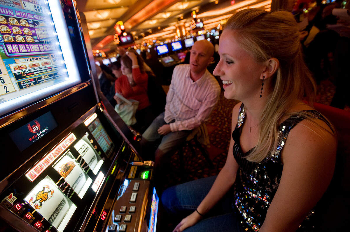 Mark Kroon of Sacramento, left, and fiance Chloe Lee of Sacramento play slots at the Red Hawk Casino in Shingle Springs on the first day it was open to the public in December 2008.