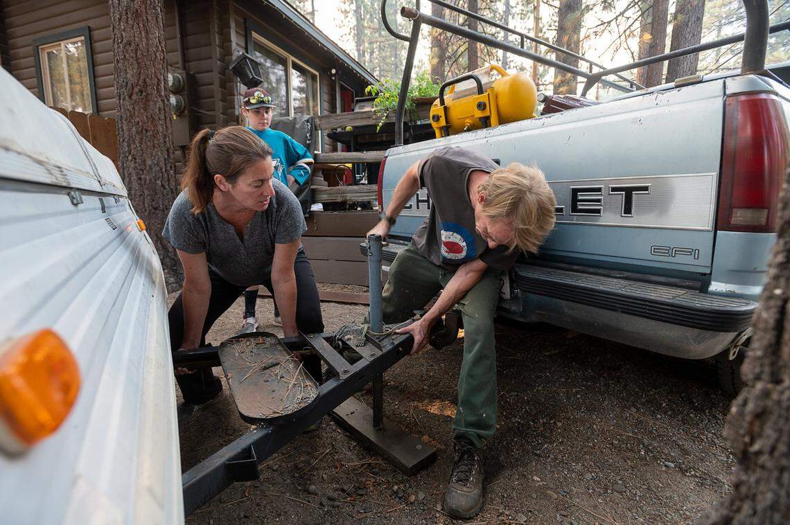 Corinne Kobel and Jess Anderson attach a camper to tehir truck while son Ethan, 11, watches as they prepare to evacuate South Lake Tahoe during the Caldor Fire on Monday, Aug. 30, 2021.