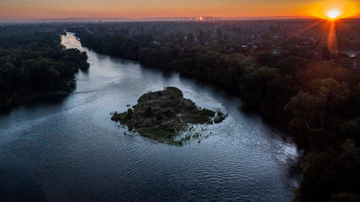 The sun sets on the American River Parkway on Monday, June 27, 2022 near the Watt Ave. bridge.  Sacramento County is depending on city water for a huge new development in Natomas, but there is no agreement. 
