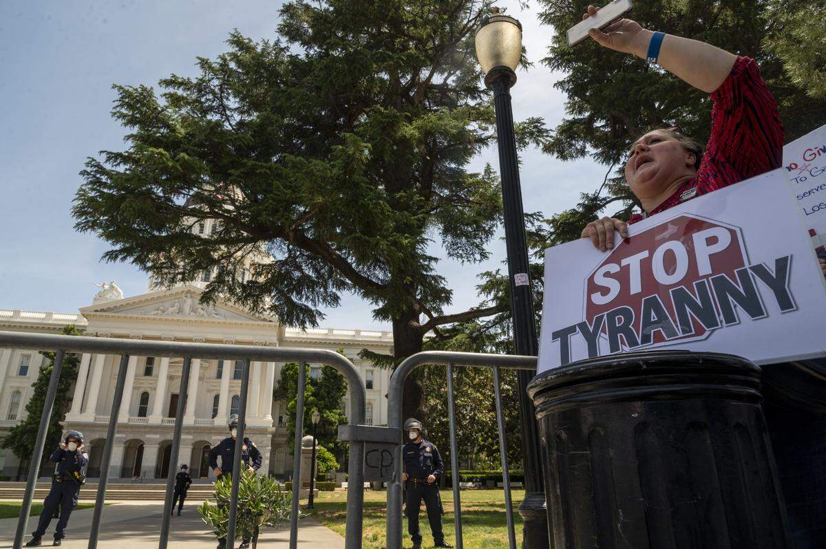J.C. Carpenter from Yuba City holds a “Stop Tyranny” sign as she joins protesters gathering on 10th Street in Sacramento on Thursday, May 7, 2020, to rally against Gov. Gavin Newsom’s stay-at-home order during the coronavirus outbreak.