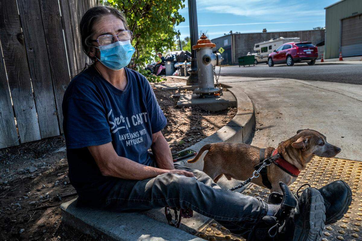 Mary Simmons, 64, sits on a curb with her Chihuahua Snickers in May after police cleared the lot where she was camping near Lexington Street and Dixieanne Avenue in Old North Sacramento. She had been hoping to get a tiny home. “Where are the tiny homes at? They’re not doing anything for homeless, just shifting us from one place to another,” she said.