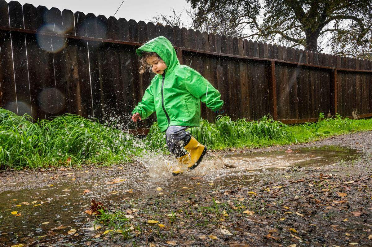 Two and a half-year-old Sepehr Emam splashes a puddle near his home at Curtis Park in Sacramento on Monday, Dec. 13, 2021, as he and his parent Taraneh enjoyed a short outdoor break as the storm passes through the area.