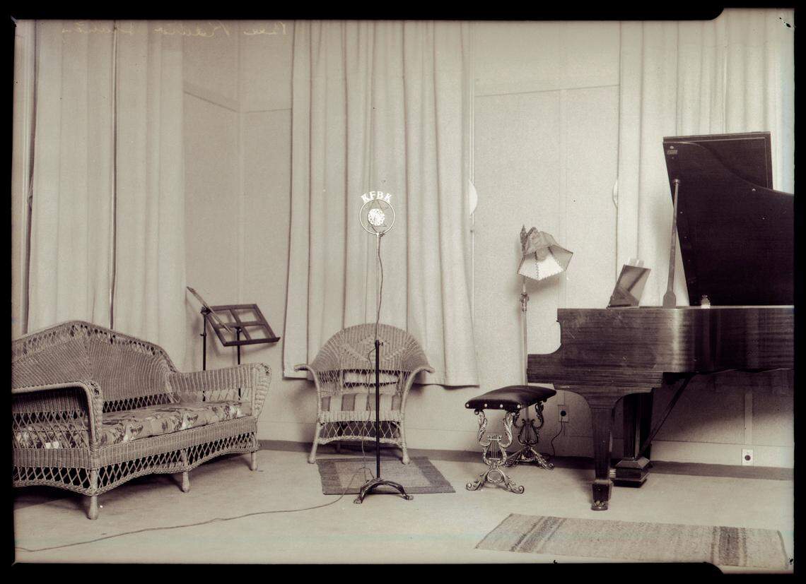 The KFBK annoucing booth early in the Sacramento radio station’s history consisted of a microphone and a piano. Words written on the back of the negative at top right say “Bee radio station.”