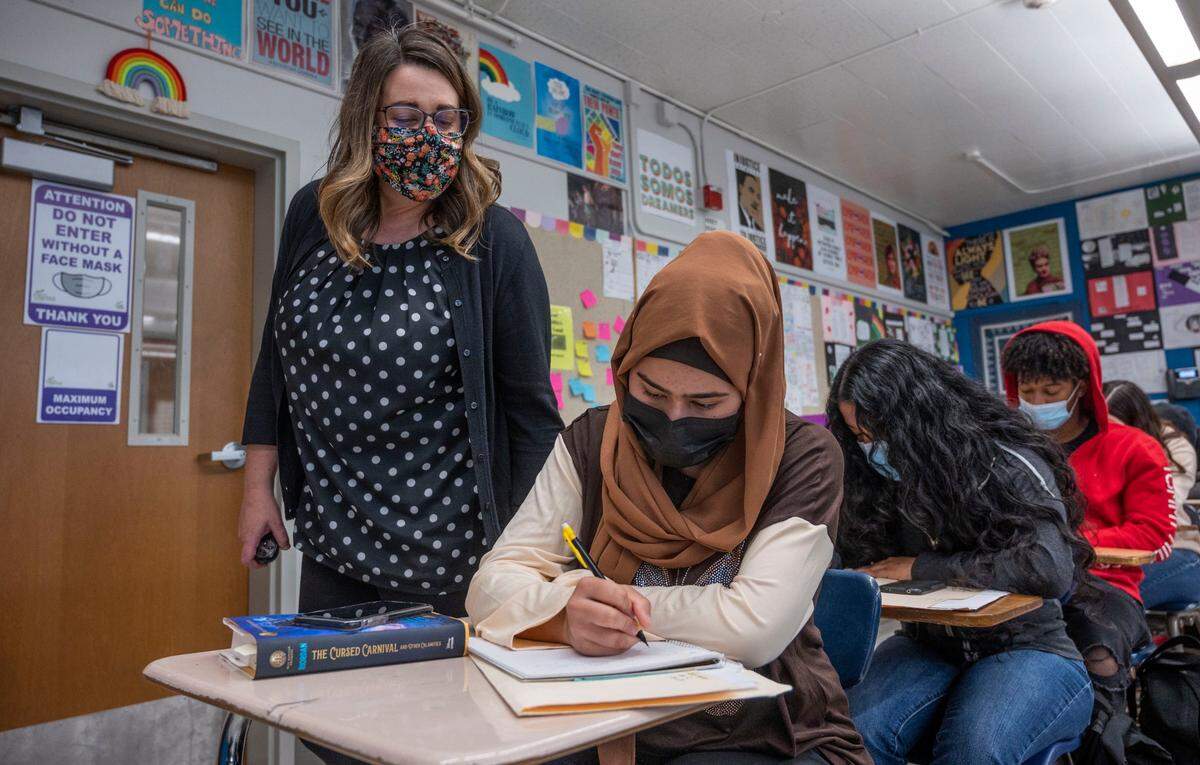 Luther Burbank High School English teacher Nichole Scrivner looks over the shoulder of senior Yanira Rodriguez during a writing assignment on April 4. Sacramento City Unified schools and Sacramento County saw a dip in enrollment after the start of the pandemic.