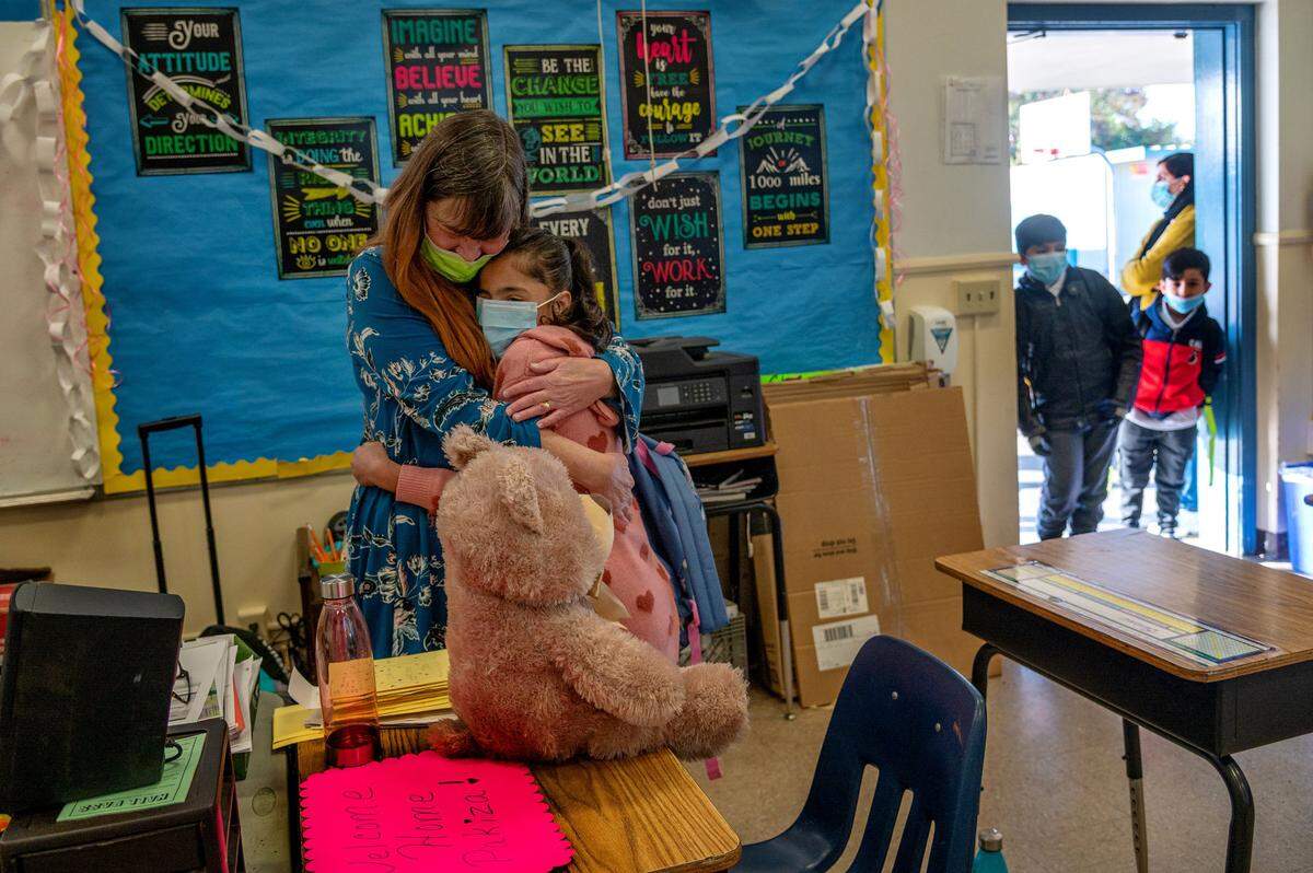 Fourth grade teacher Kelly Melvin emotionally hugs her Afghan student Pakiza, 9, after giving her a teddy bear to welcome her back to Ethel I. Baker Elementary School in Sacramento on Monday. Pakiza’s brothers Faizan, 8, and Raihan, 6, stand in the doorway. The three students were stranded with their parents in Afghanistan when the Taliban took over the country. “I’m going to take good care of her. I put her desk right here by me,” Melvin said to Pakiza’s mother Huma afterwards.