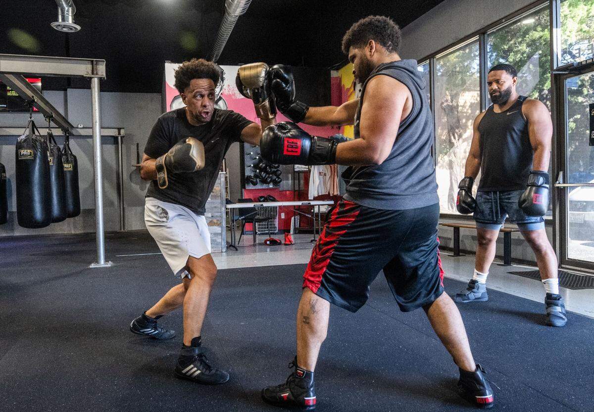 Sacramento Bee opinion columnist LeBron Hill, right, blocks a punch from Sacramento State president Luke Wood during a boxing workout last month at Flawless Boxing & Fitness in Sacramento.