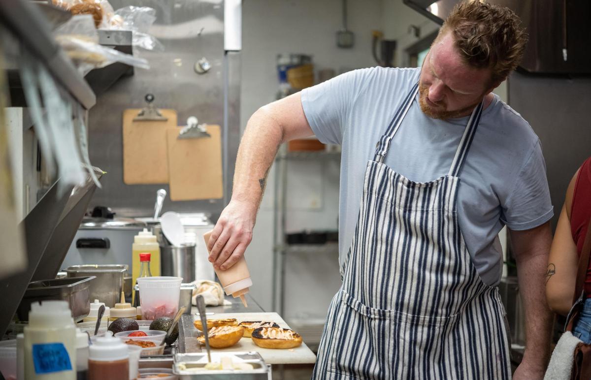 Chef-owner Matt Brown works to finish a tripleta — a sandwich with grilled chicken, bacon and a slow-roasted pork called pernil — at Bodega Kitchen & Cocktails on Thursday.