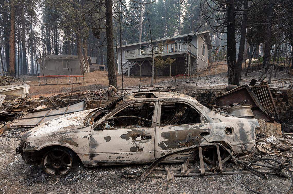 The Freitas family home stands untouched behind a neighbor’s burned car on Tyler Drive in Grizziy Flats. on Tuesday, Aug. 17, 2021, after the Caldor Fire burned a number of homes nearby.
