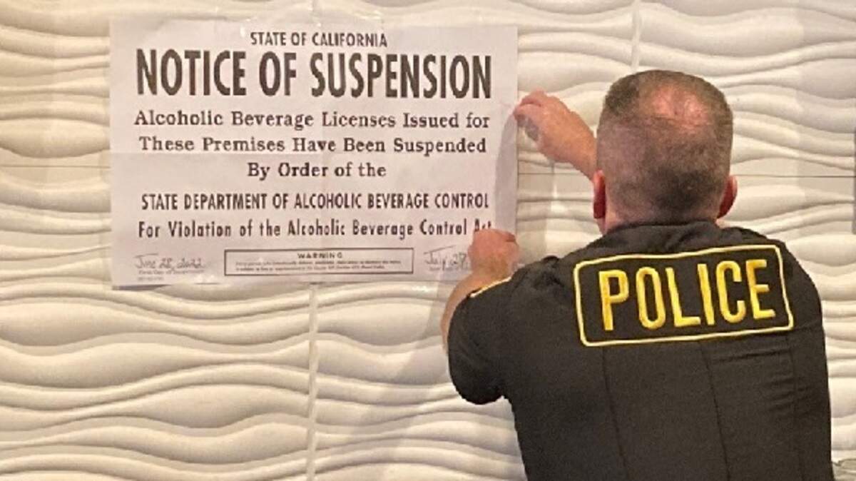An officer posts a notice of suspension at La Cabana on Folsom Boulevard on June 28, 2022. The restaurant will be prohibited from selling alcohol for 30 days.