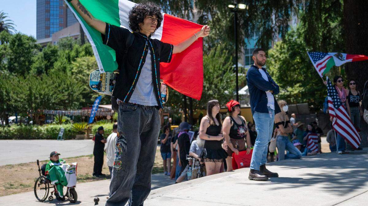 Matthew Loarca stands in Cesar E. Chavez Plaza holding a Mexican flag during a protest against U.S. Immigration and Customs Enforcement in downtown Sacramento on Monday, June 9, 2025.