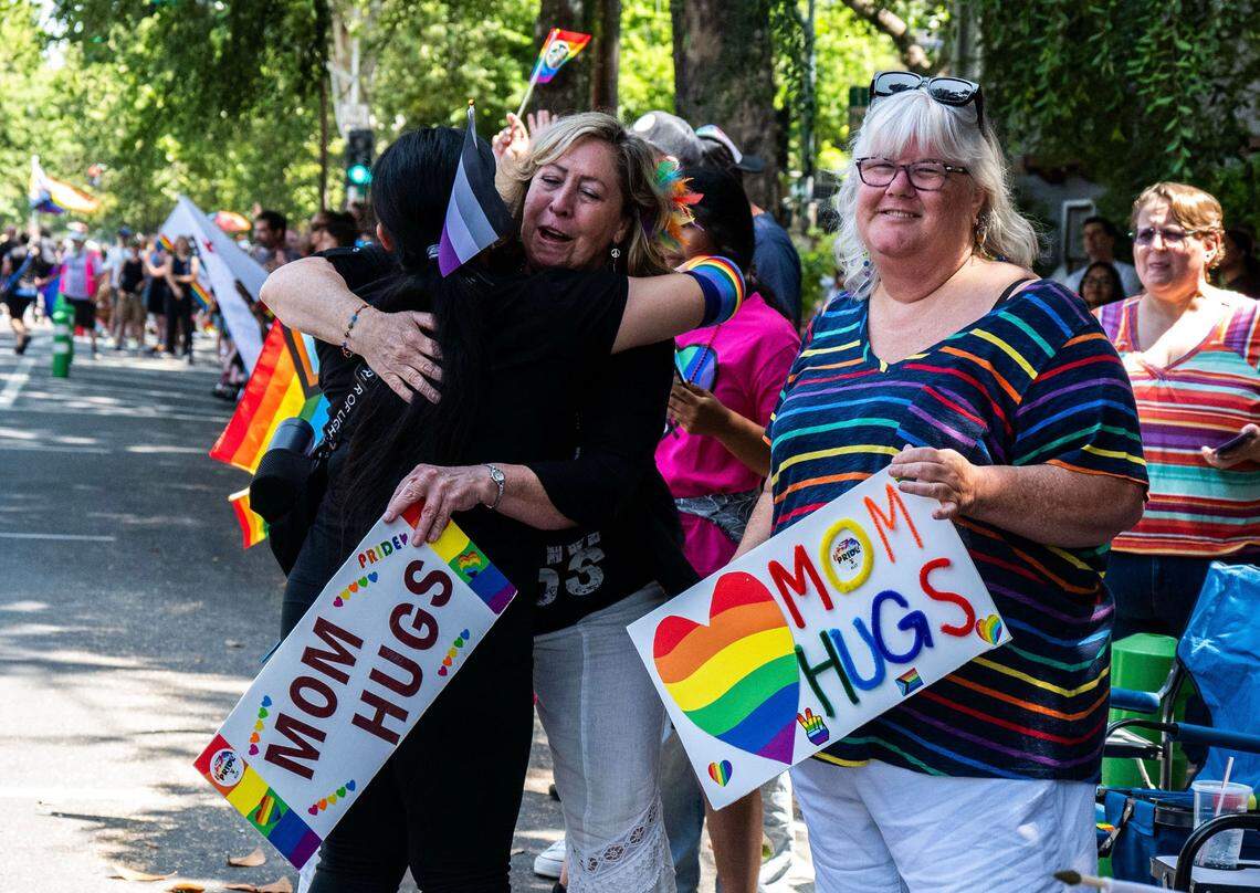 Sharon Ballestero, left, and Anne Russ, right, offer “mom hugs” to attendees at the Sacramento Pride March on Sunday.
