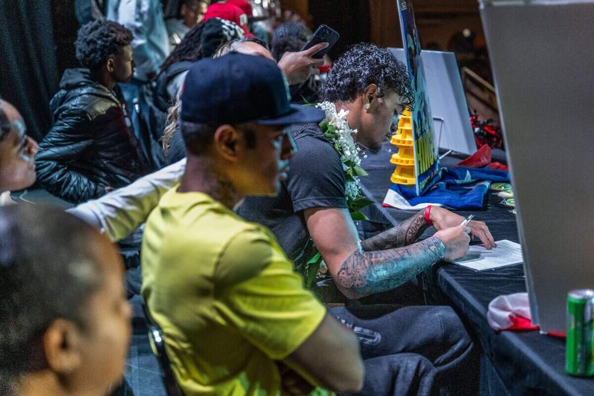 Grant High School defensive back Kingston Lopa signs his letter of intent with the University of Oregon on Wednesday during a National Signing Day event at the school.