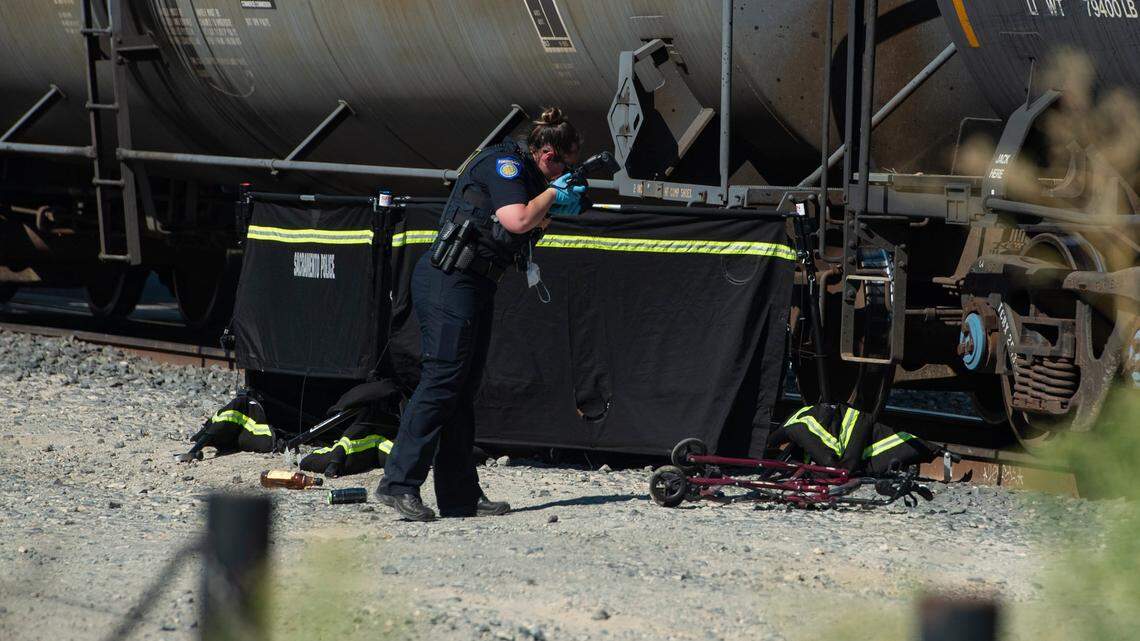 A Sacramento Police crime scene investigator takes photos in front of a screen obscuring the remains of a pedestrian fatally struck by a train on Monday in midtown Sacramento.