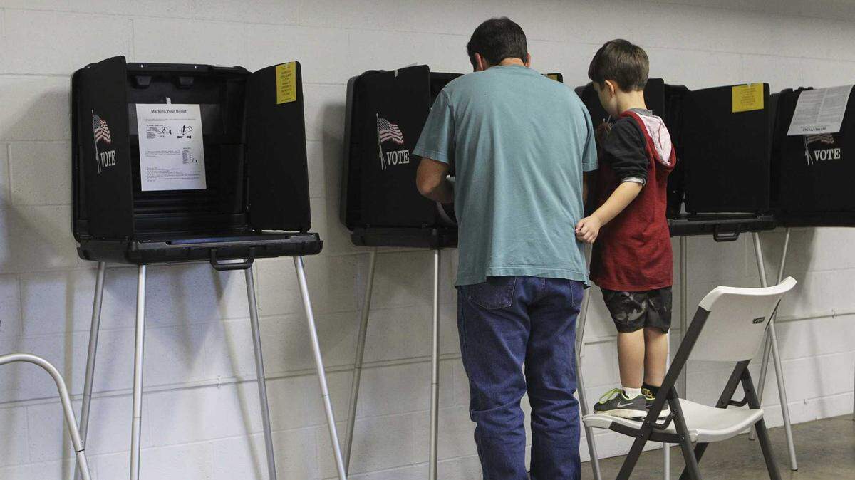 Lanson Zaniroli, 4, watches his father Lance vote at First Christian Church on Nov. 4, 2014, in Shasta County. On Friday, the California Legislature approved a bill that limits when local governments can count election ballots by hand. The bill was aimed at Shasta County, which had been preparing to hand count election ballots after local leaders voted to get rid of the voting machines they use to tabulate votes.