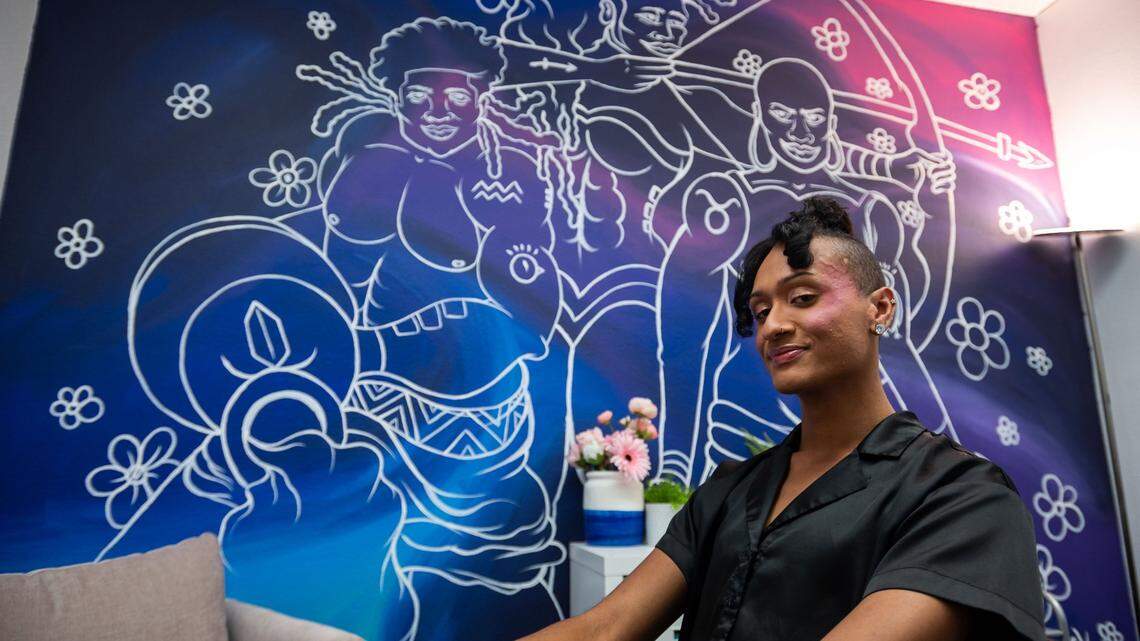 Aaron Armer, a lead HIV tester and case manager at Marsha P. Johnson Center South, sits in front of a mural by Aik Brown at the center, which is a new extension of the Sacramento LGBT Community Center on Stockton Boulevard, on July 14, 2021.