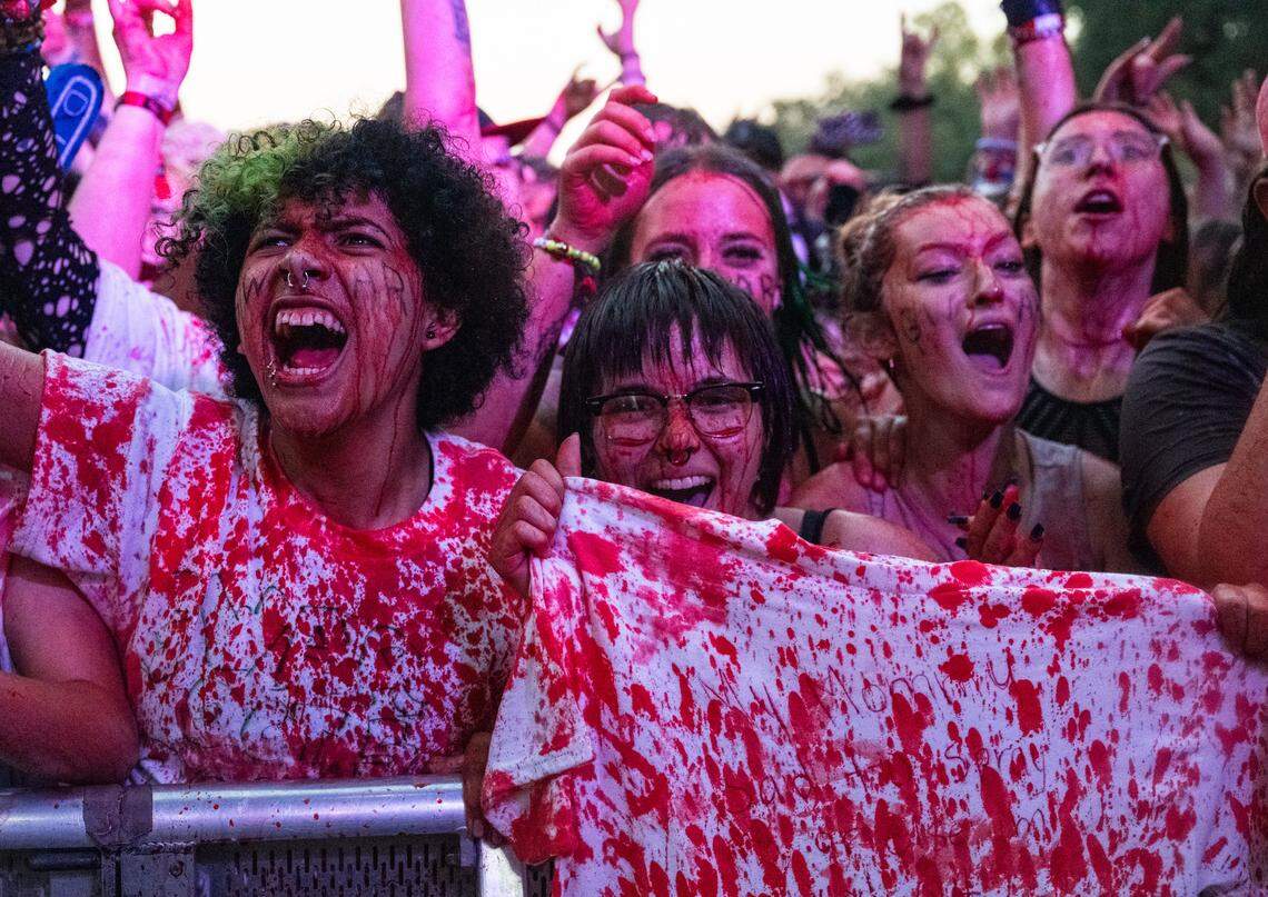 Marshall Fields, left, Kai Cruz, center, and Leyna Burkhevics, friends who traveled from Washington, cheer as they are drenched in fake blood during Gwar’s performance at the Aftershock festival on Sunday, Oct. 5, 2025, in Sacramento’s Discovery Park.
