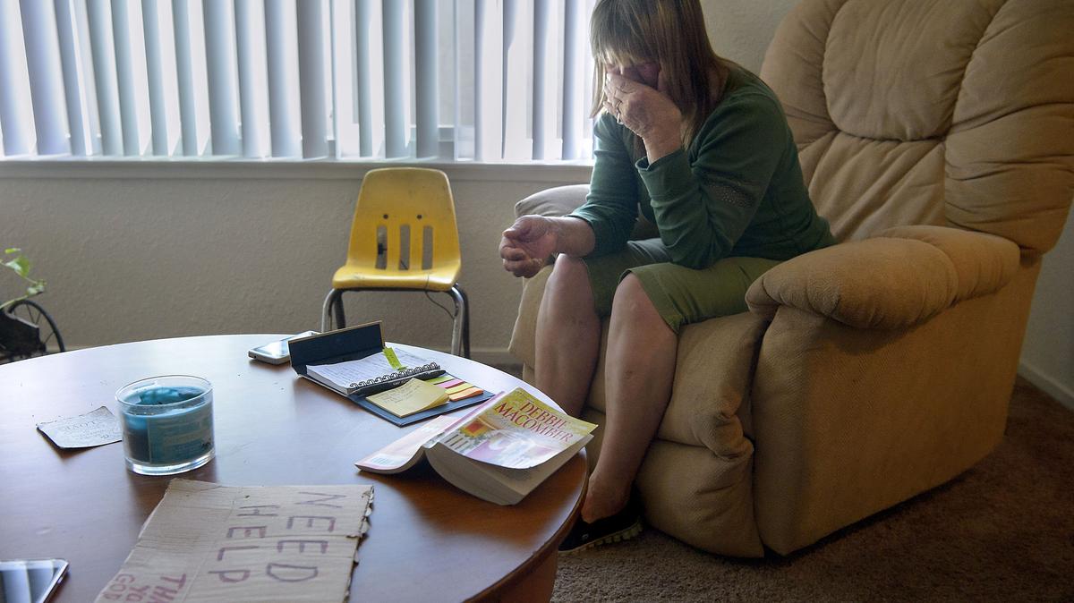 With her cardboard sign on the table at left, Katherine Ann Wahl remembers her years living on the streets, at her home in Sacramento on Wednesday, April 4, 2018. Wahl was homeless for 31 years before finding permanent housing through the Winter Triage Shelter on Railroad Drive.