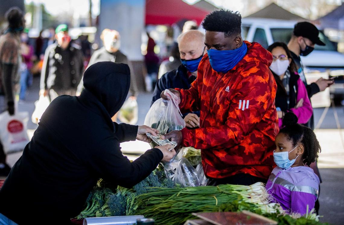 Uzoma Okoro, of Sacramento, and his daughter Olivia, 6, buy produce at the Sunday Certified Farmer’s Market under Highway 50 on Feb. 28, 2021, the last day before it temporarily moves to Arden Fair mall because of a construction project on the W/X freeway. The market reopens March 21 at the new spot.