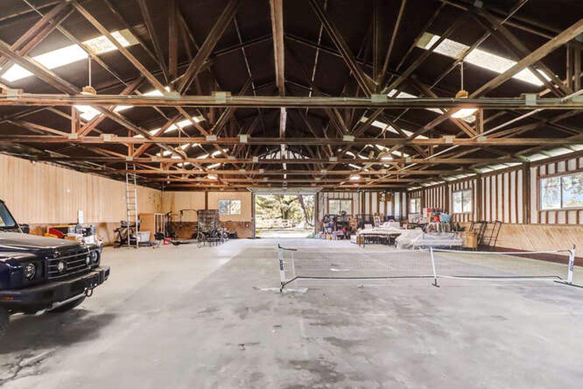 A 9,000-square-foot barn and workshop that was originally a practice arena for equestrian lovers now houses vehicles, a gym and a pickleball court.
