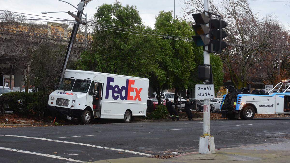A FedEx delivery van is being towed off the curb after colliding with a utility pole on 29th Street in midtown Sacramento on Monday, Dec. 22, 2025. The vehicle was driving the wrong way on the one-way street before it crashed.