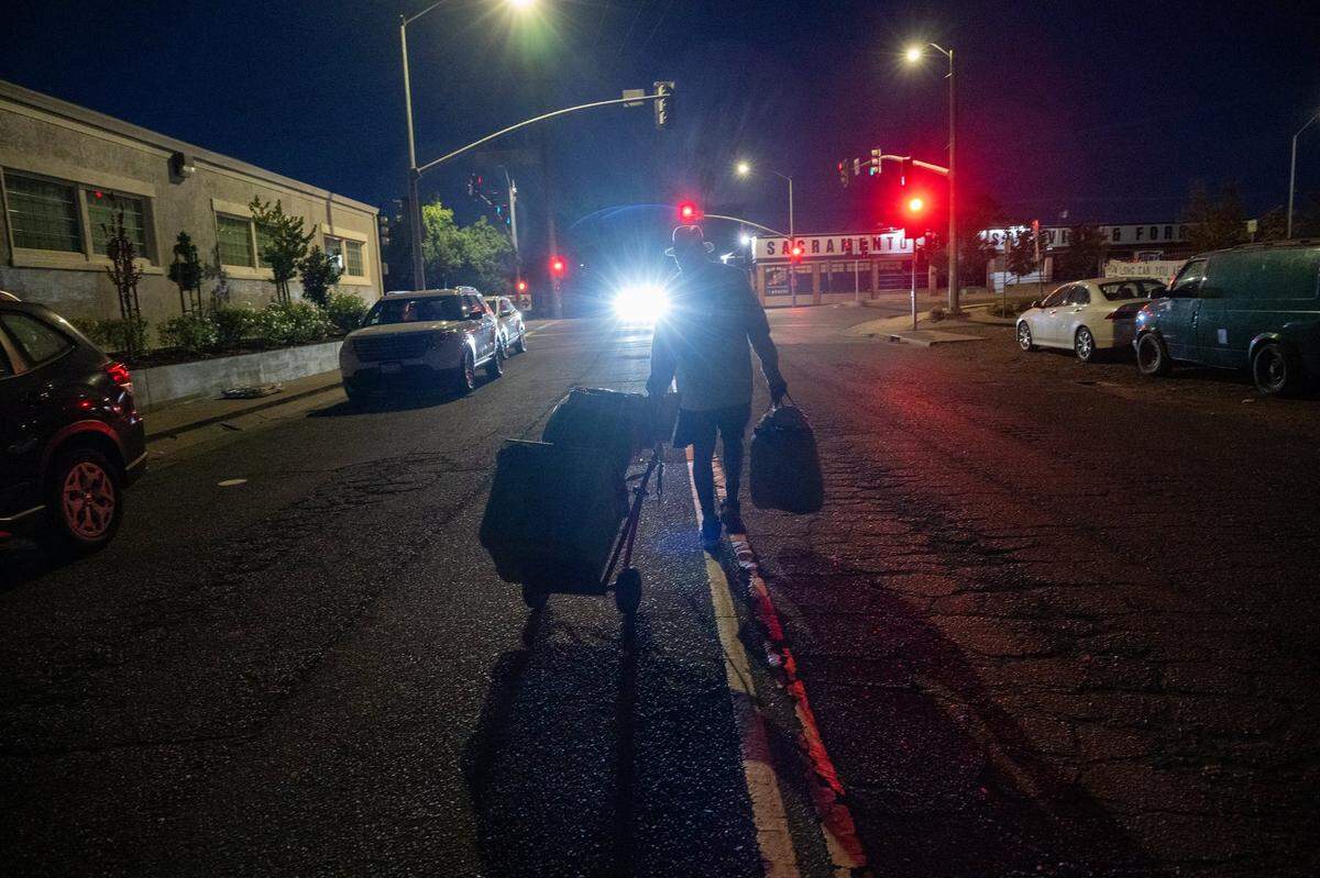A homeless resident from Camp Resolution pulls his belongings on a cart in around 5:30 a.m. on Monday, before city of Sacramento crews arrived to remove the self-governing homeless encampment on Colfax Street.