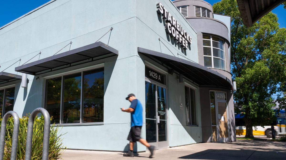 A man walks past a Starbucks coffee shop on his way back to his car after reading a sign on the door of the recently closed Jamba Juice shop at 1429-B Broadway in Sacramento on Thursday.