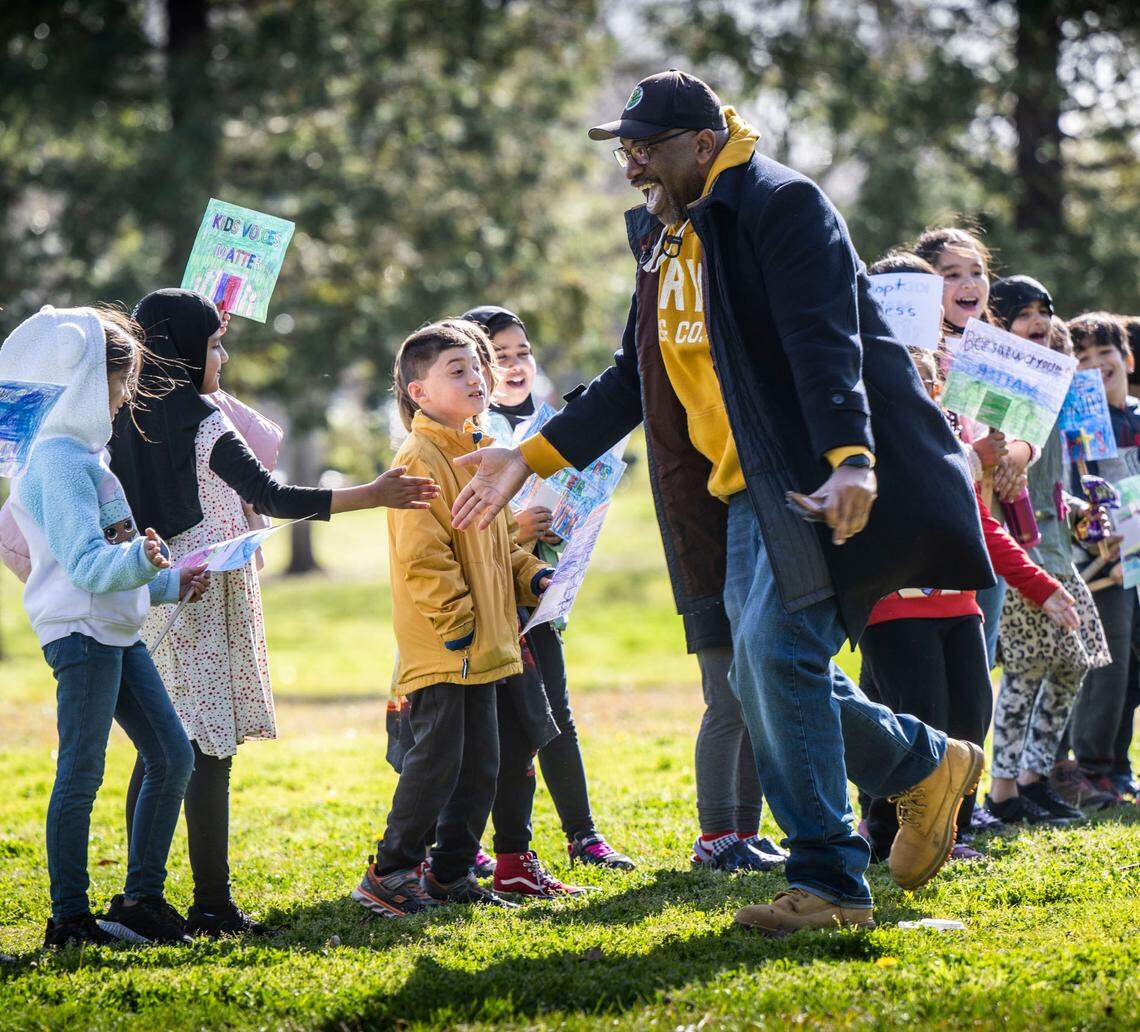 Jamal Hicks, principal at Kelly-Dyer Elementary School, shakes hands with second-grade students at a march on Feb. 17.