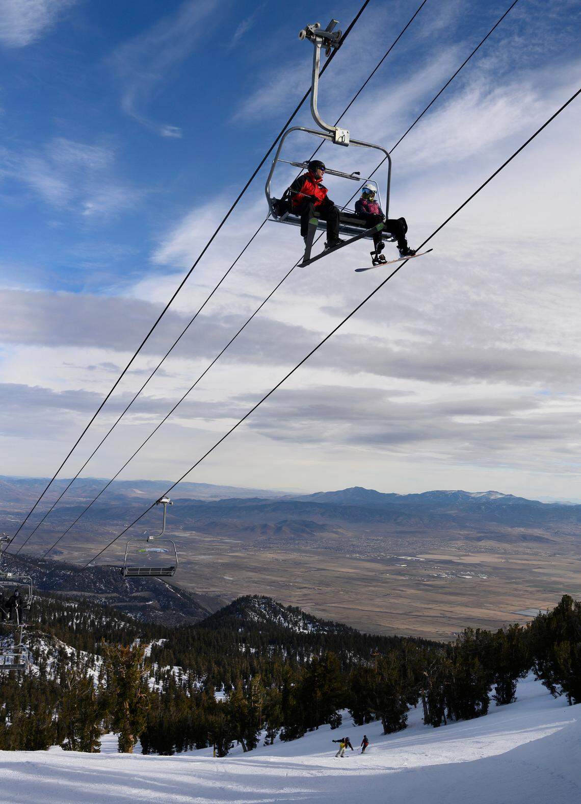 Two skiers ride the Dipper Express lift – which starts in Nevada and ends in California – in January at Heavenly ski resort as the Sagebrush State’s dry Carson Valley provides contrast in the background.