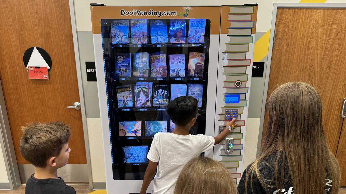 Peyton Vaughn, 7, selects a book July 17 from the vending machine at the Rancho Cordova Youth Center, while three other students wait for their turn.
