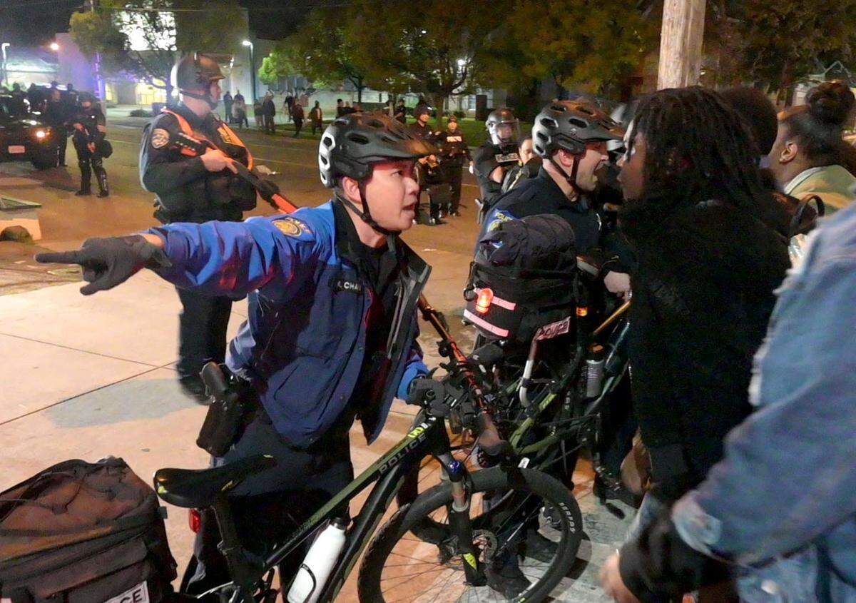 A Sacramento police officer directs protestors during a Stephon Clark march in the Fabulous 40s on Monday. The march ended with more than 80 people arrested.