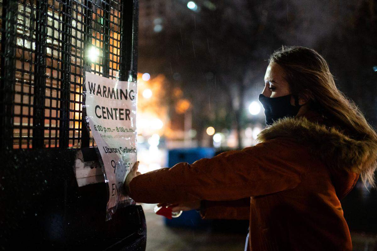 Lauren Groves, an Emergency Operations Center coordinator with the City of Sacramento, tapes up a sign for the opening of the warming center at Tsakopoulos Library Galleria outside the entrance on 9th Street across from Cesar Chavez Plaza on Wednesday, Jan. 27, 2021, in downtown Sacramento. City officials said it will be open 8 p.m. to 8 a.m. until further notice.