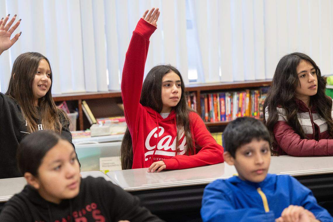 Karla Acevedo Perez raises her hand to answer a question at Live Oak Elementary School near Lodi in October. She is among the 72,257 students in California eligible to participate in the Migrant Education Program, a federal initiative intended to help students with supplementary after-school and summer programs.