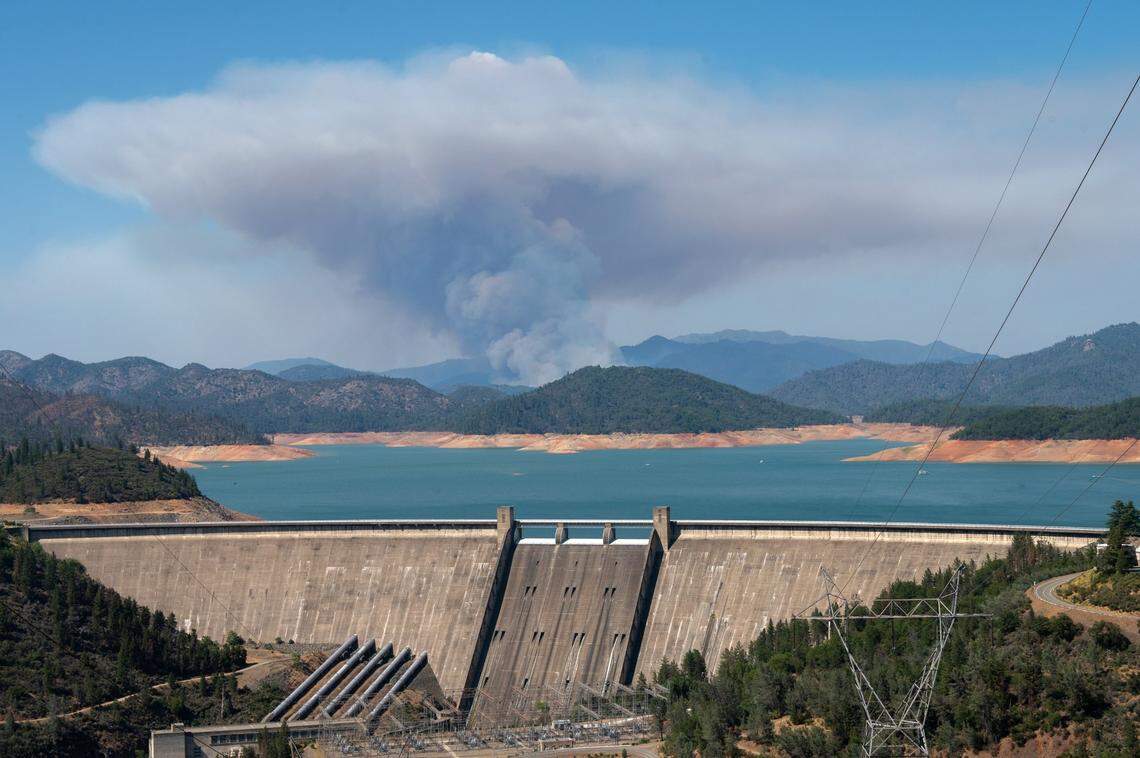 A ring of exposed lake bed surrounds the water held back by Shasta Dam on June 30, as the Salt Fire burns north of the lake. A proposal to raise the dam 18 feet, increasing the lake’s capacity 18%, is currently seeking funding.