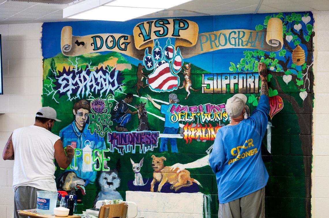 Inmates work on a mural showcasing the Valley State Prison dog program at the Chowchilla facility on July 27..