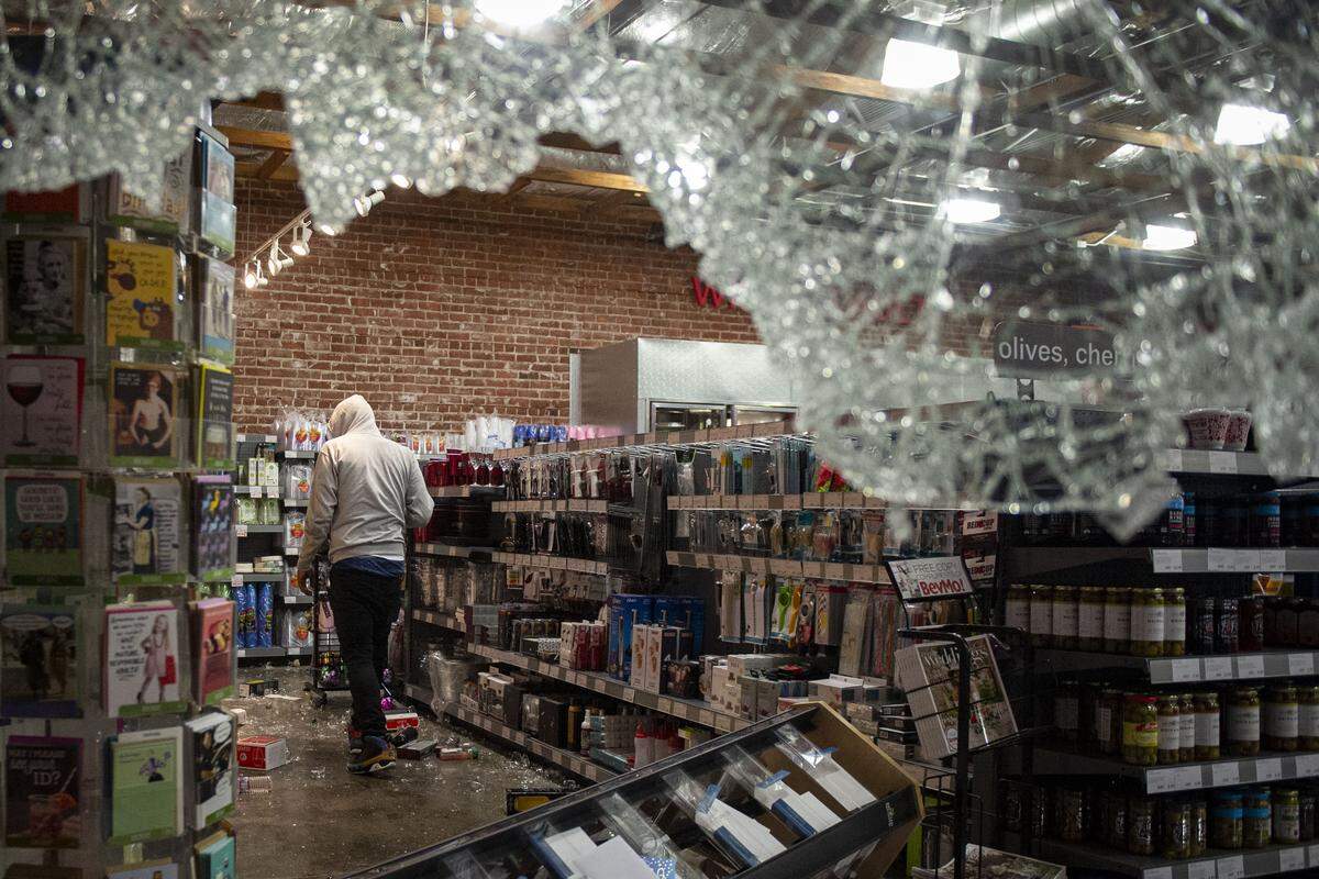 Looters enter BevMo on J Street in downtown Sacramento after smashing windows during a night of vandalism following George Floyd protests, Saturday.