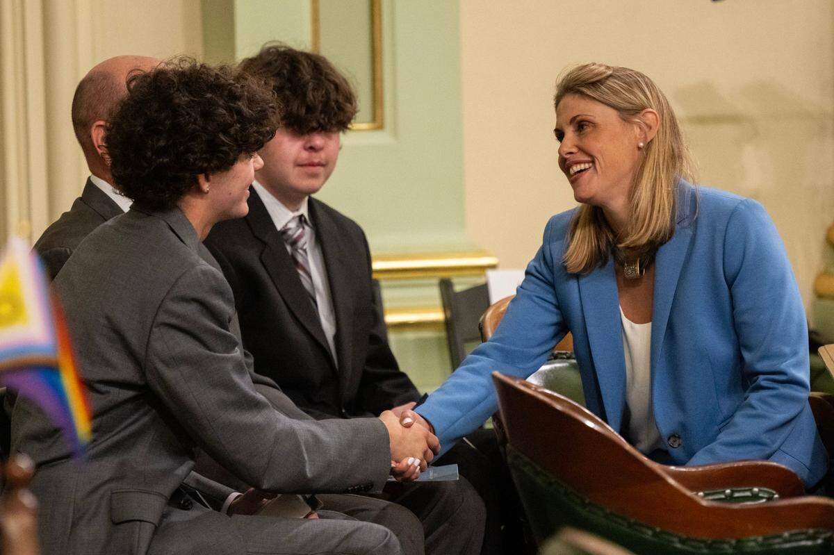 Assemblymember Maggy Krell, D-Sacramento, practices shaking hands with her son Tyler during the first meeting of the new legislative session on Monday.