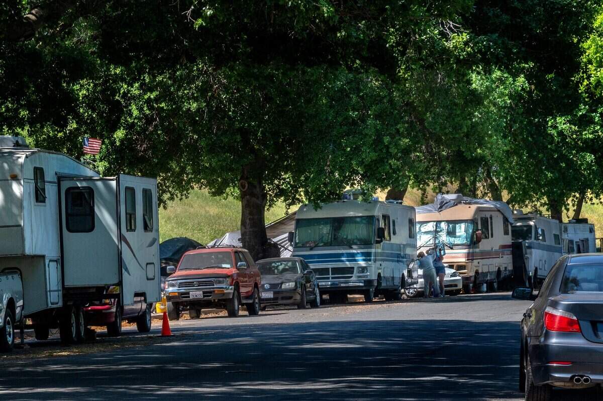 Two women refill a motor home with water on Lathrop Way in Sacramento on April 21. Campers said it’s been hard to get water, and the water at hydrants have been turned off. On most days, there are almost 100 vehicles belonging to the homeless, who say they’ve been given no other options but to park their vehicles within the city. Many said they had never heard of a safe ground for parking.