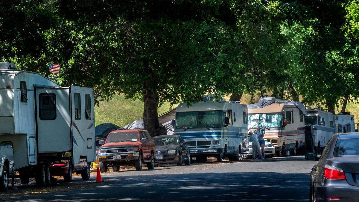 Two women refill a motorhome with water on Lathrop Way in Sacramento in 2021. On most days there are at least 95 vehicles belonging to the homeless, who say they have been given no other options but to park their vehicles within the city.