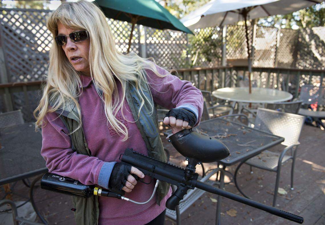 Bear League executive director Ann Bryant stands ready with her paintball gun (she uses chalk balls instead of paint balls) should she need to scare a black bear which hangs out in the safety of a pine tree and bushes behind a pizza restaurant in Kings Beach, Calif. on Tuesday, September 24, 2013.