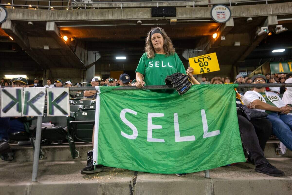 An A’s fan holds a “sell” flag while watching a game against the Tampa Bay Rays last month at the Oakland Coliseum.