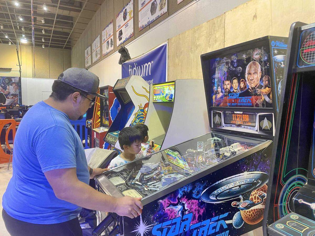 Jeff Garzona plays pinball on Monday while his son, Liam Garzona, watches. Garzona said that he used to play pinball at the laundromat near his house.