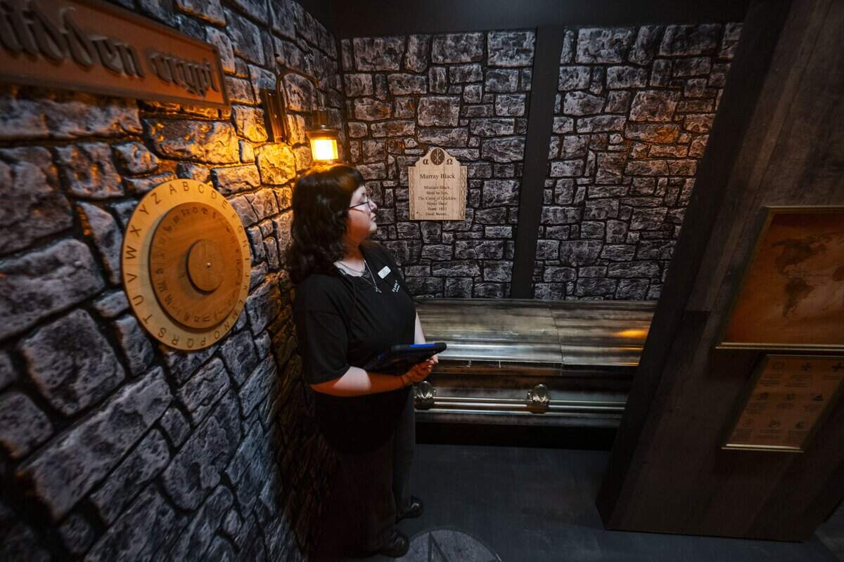 Cha Wally-Bowser, a game master at Escapology, stands next ot the coffin in the final room of the “7 Deadly Sins” game during the venue's grand opening at Downtown Commons on Wednesday.