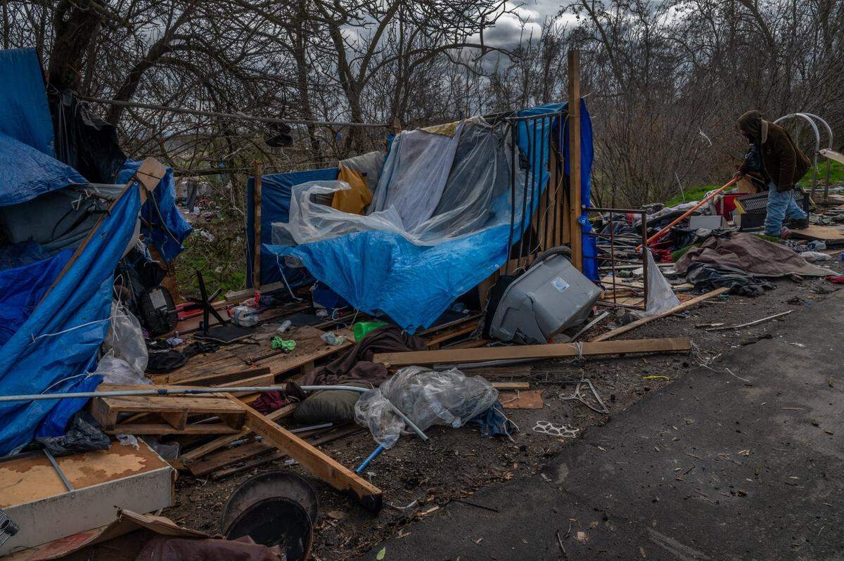 Clarence Cooper Jr. sifts through debris after a windstorm at a homeless encampment near Basler and N. 18th streets in Sacramento on Wednesday, Jan. 27, 2021. “I dove in a smaller tent and it took off. I ain’t ever seen a storm that strong,” said Cooper.